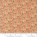 A close-up of a fabric pattern featuring small pink and blue flowers with beige leaves on a warm tan background, with a measuring ruler along the bottom edge showing scale. The brand name 'moda' is visible at the bottom.
