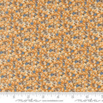A close-up of a fabric pattern featuring small orange and yellow flowers with brown centers and scattered light blue accents, shown with a ruler along the bottom edge and a Modas Fabrics watermark.