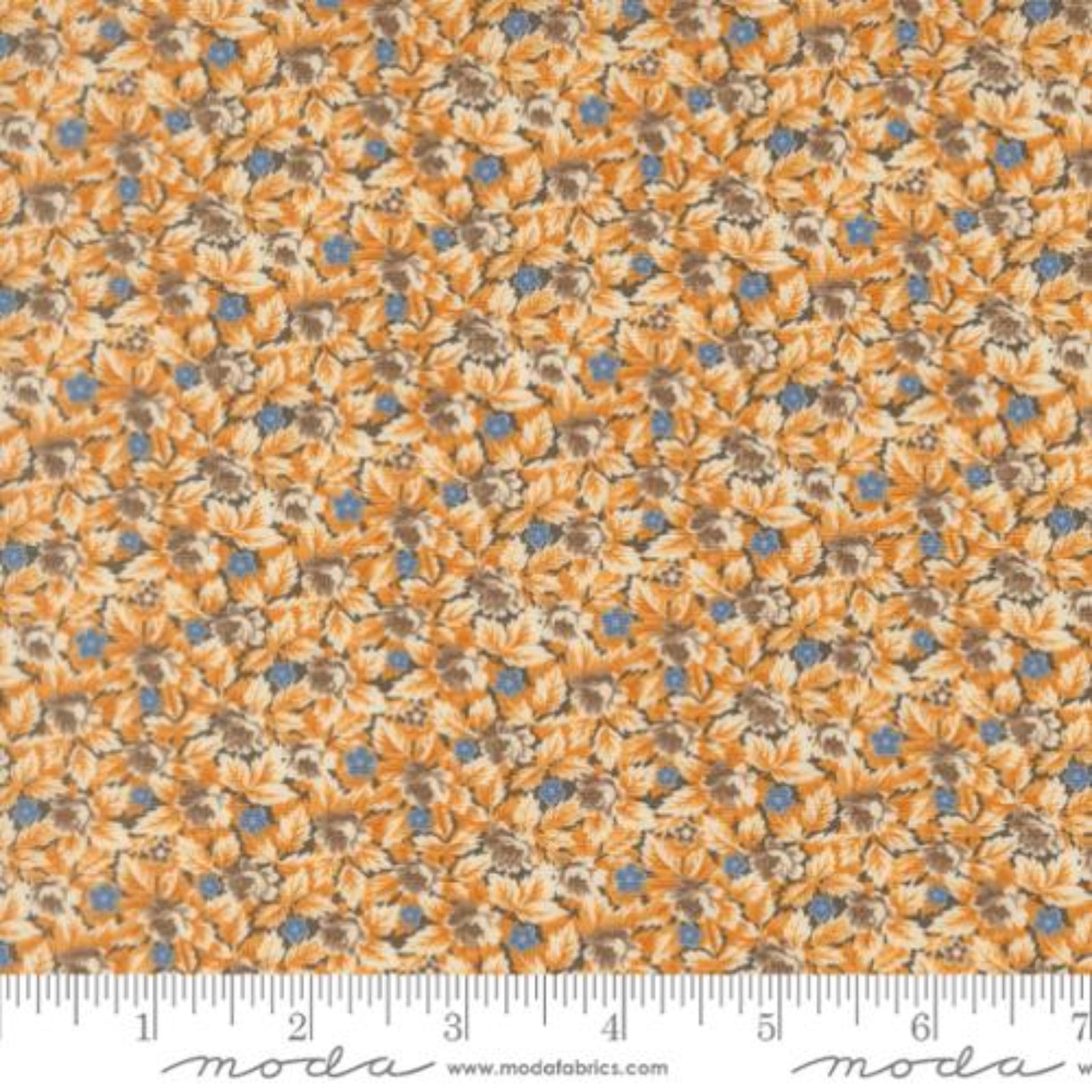 A close-up of a fabric pattern featuring small orange and yellow flowers with brown centers and scattered light blue accents, shown with a ruler along the bottom edge and a Modas Fabrics watermark.