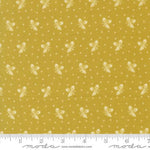 Yellow fabric with a repeating pattern of small white bows and dots, shown with a measuring ruler along the bottom edge.