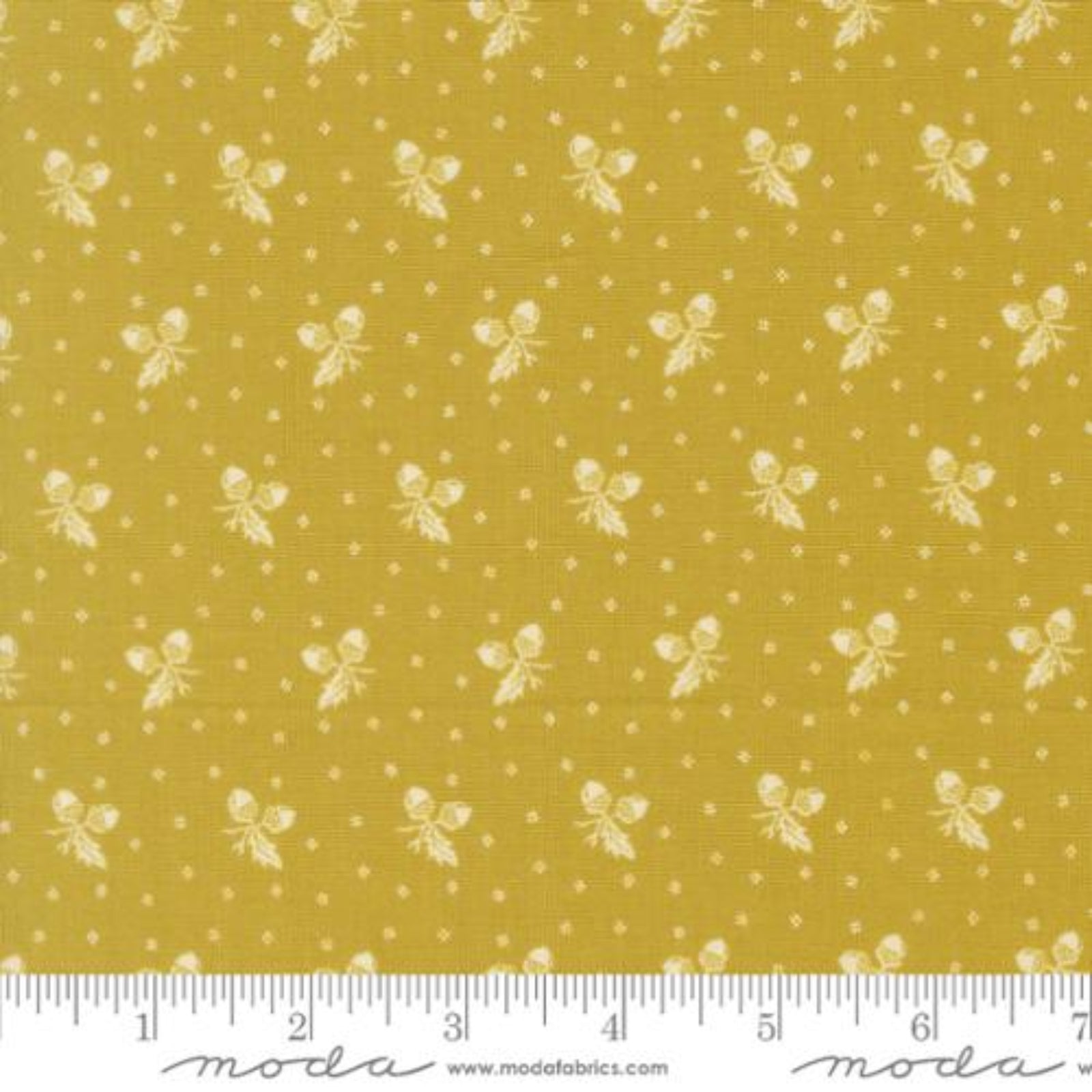 Yellow fabric with a repeating pattern of small white bows and dots, shown with a measuring ruler along the bottom edge.