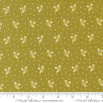 A close-up of fabric showing a repeating pattern of small cream butterflies and dots on an olive yellow background, with a ruler along the bottom edge and Modas fabric branding at the bottom.