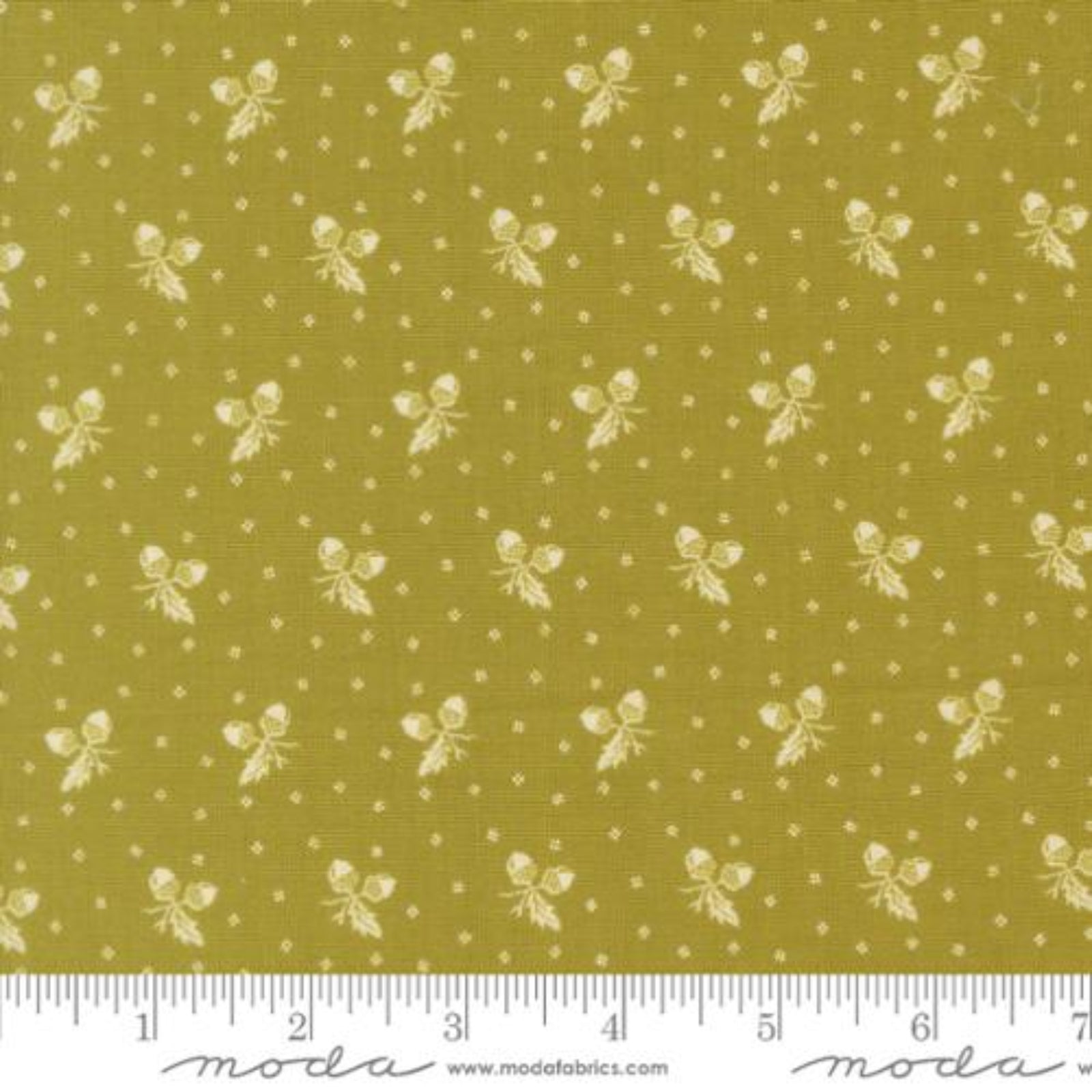 A close-up of fabric showing a repeating pattern of small cream butterflies and dots on an olive yellow background, with a ruler along the bottom edge and Modas fabric branding at the bottom.