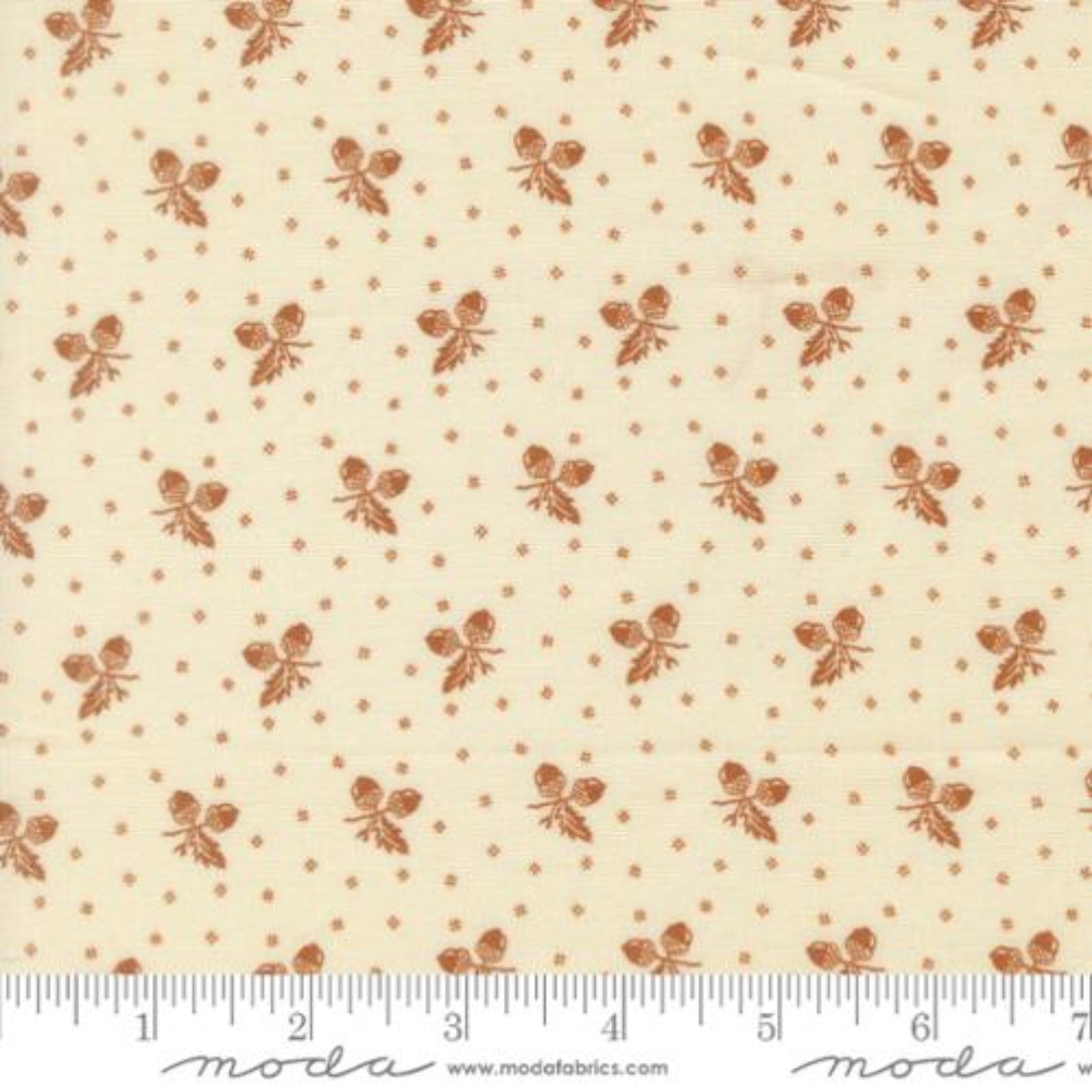 A close-up of a fabric pattern featuring small brown floral motifs and tiny brown dots on a warm cream background, with a ruler along the bottom edge showing scale. The brand name 'Moda Fabrics' is visible at the bottom.