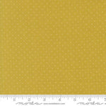 Yellow fabric with a small white polka dot pattern and a white ruler along the bottom edge showing measurements.