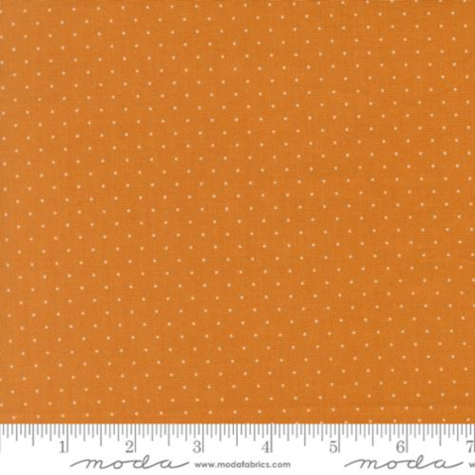 Orange fabric with a small white polka dot pattern, shown with a measuring ruler at the bottom to indicate scale. The brand name 'Moda Fabrics' is visible on the ruler.