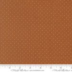 A close-up of a fabric pattern featuring a warm rust-orange background with a repeating pattern of small white dots, with a white ruler at the bottom showing measurements and the Modas Fabrics logo.