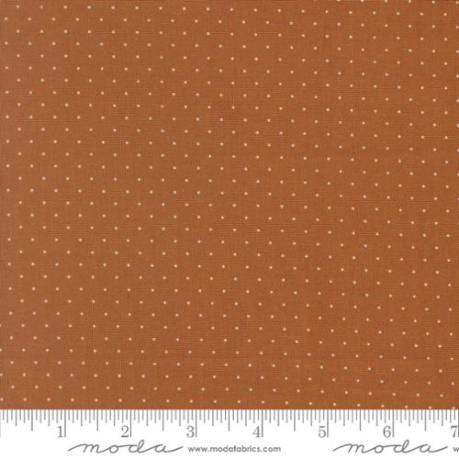 A close-up of a fabric pattern featuring a warm rust-orange background with a repeating pattern of small white dots, with a white ruler at the bottom showing measurements and the Modas Fabrics logo.