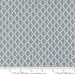 A close-up of a fabric pattern featuring a repeating blue and cream ikat or medallion design, with a ruler at the bottom indicating scale. The brand name 'Moda Fabrics' is visible at the bottom.