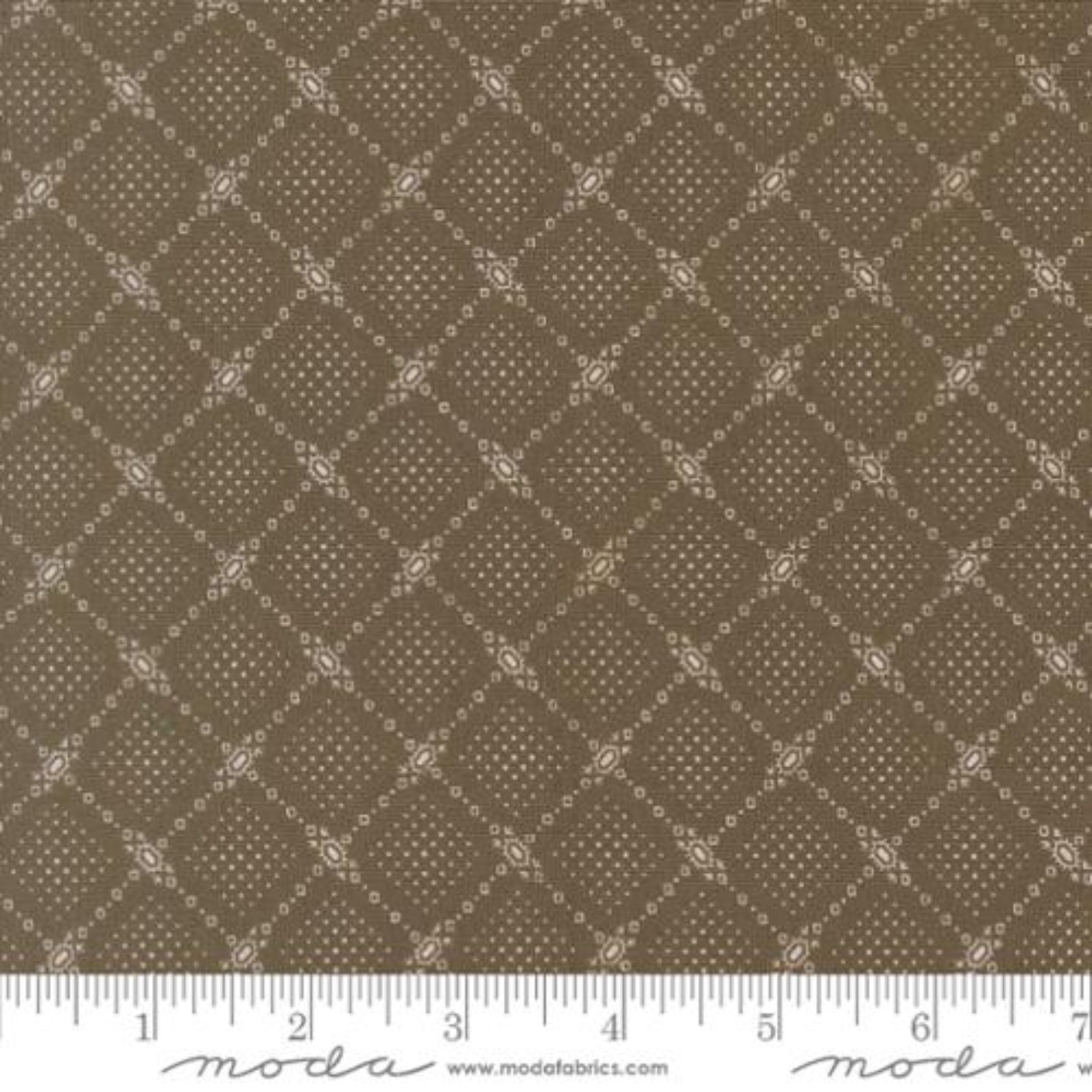 A close-up of a fabric pattern showing a repeating diamond lattice design in warm brown and beige, with a white ruler along the bottom edge and Modas Fabrics branding.