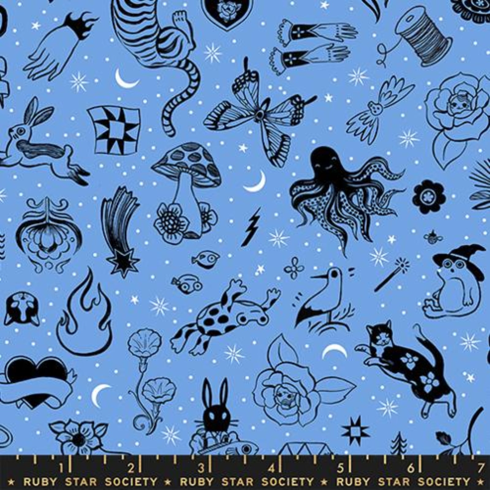 A flat lay of a fabric pattern featuring whimsical black line-art illustrations of fairies, flowers, stars, and nature motifs on a light blue background, with a Ruby Star Society ruler shown along the bottom edge.