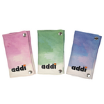 Three small fabric pouches or wallet-like accessories shown on a plain white background, each with a different watercolor-style gradient: pink to white, green to white, and blue to white. The word "addi" is printed near the bottom of each item, with small orange heart details above the letters.