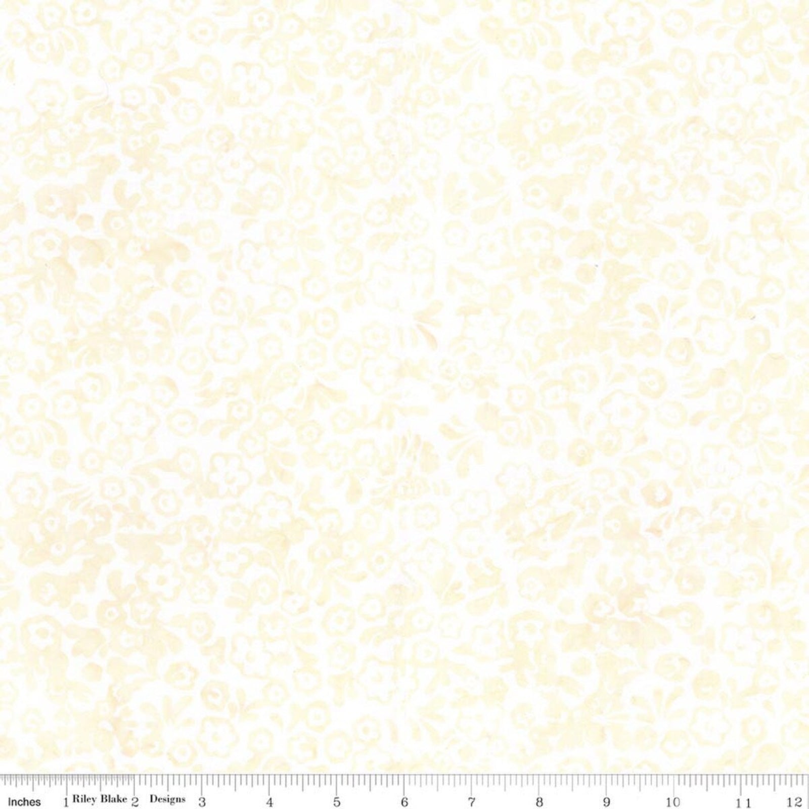 A close-up of a fabric pattern featuring a delicate, repeating damask-style floral and scroll motif in pale yellow on a white background, with a ruler scale visible along the bottom edge.
