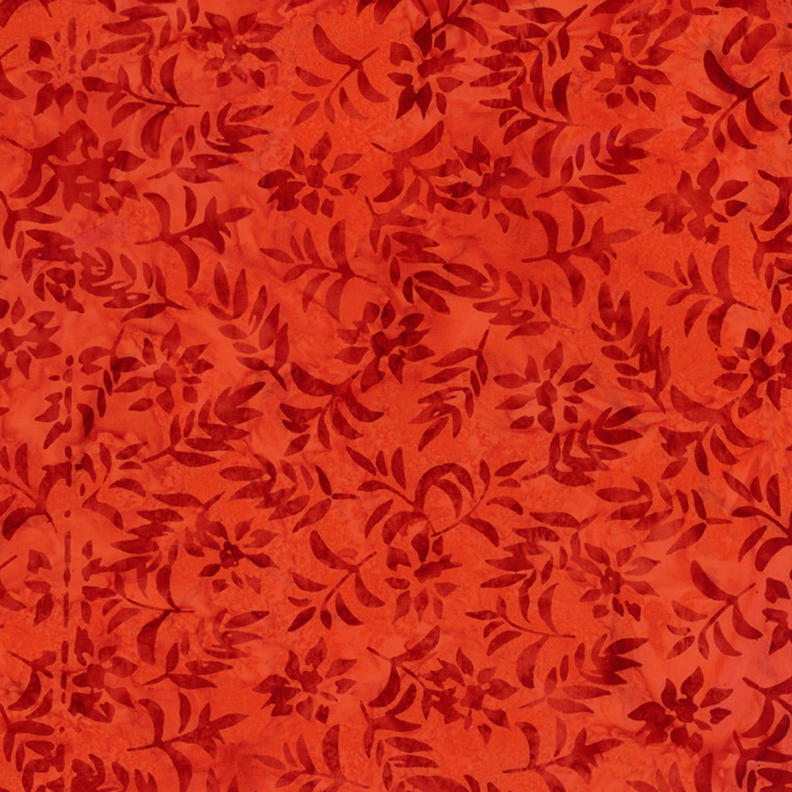 A close-up of a red-orange batik fabric with a dark red floral and leafy pattern.