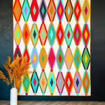Breezeway quilt with bright layered diamond blocks displayed against a dark wall.