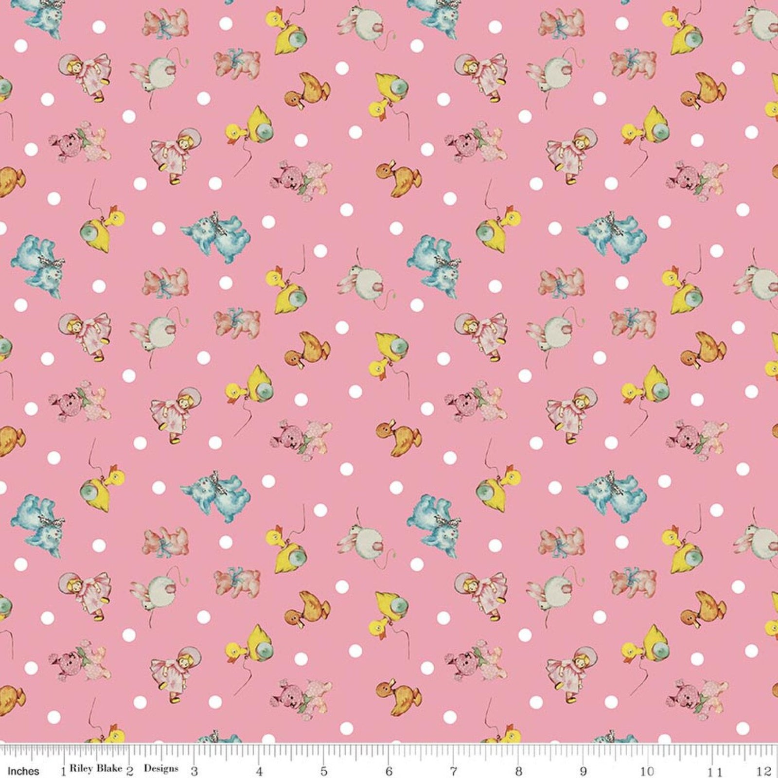 Pink fabric with a repeating pattern of white polka dots and small vintage-style illustrated characters in pastel blue, yellow, and beige. A ruler is visible along the bottom edge.