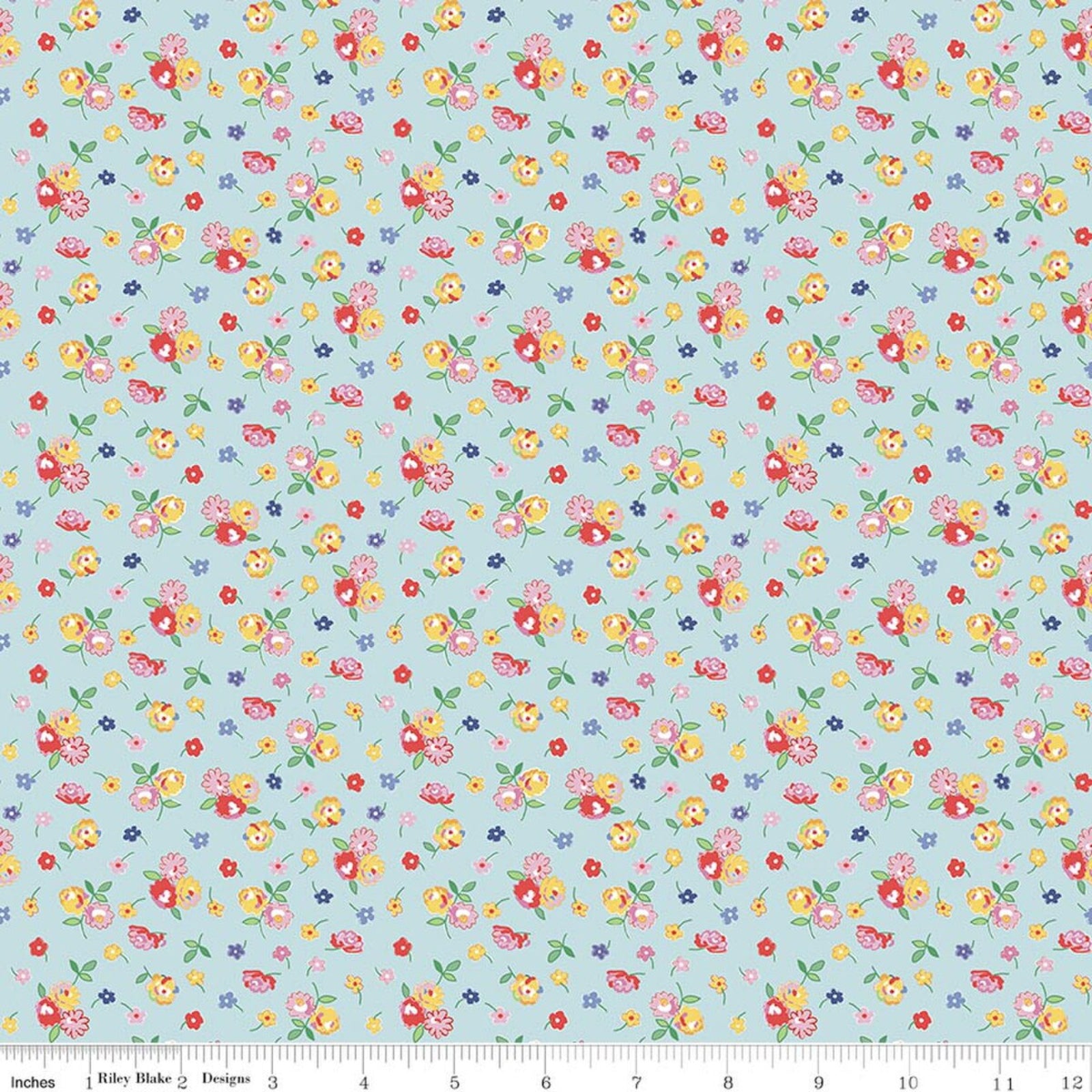 A repeating floral fabric pattern on a light blue background, featuring small yellow, red, pink, and blue flowers with green leaves. A ruler at the bottom shows the scale of the pattern.