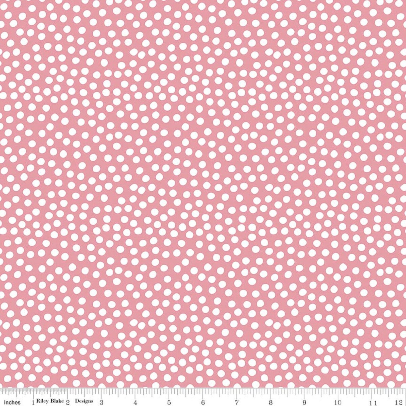 Pink fabric with a repeating pattern of small white polka dots, shown flat with a measuring ruler along the bottom edge.