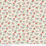 A close-up of a repeating floral fabric pattern on a warm cream background, with small pink, red, and blue flowers and green leaves. A ruler along the bottom edge shows scale in inches.