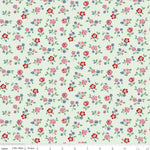 A repeating floral pattern on a pale mint green background, featuring small pink, red, and blue flowers with green leaves. A ruler along the bottom edge shows scale in inches and includes the text Riley Blake Designs.
