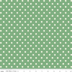 Green fabric with a repeating pattern of white polka dots, shown flat with a ruler along the bottom edge for scale.