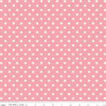 Pink fabric with a repeating pattern of white polka dots, shown flat with a ruler along the bottom edge for scale.
