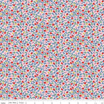 A close-up of a repeating floral fabric pattern with small red, blue, pink, yellow, and green flowers on a pale pink background, with a ruler along the bottom edge showing scale.