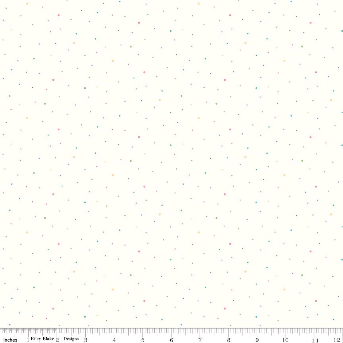 A repeating pattern of tiny multicolored dots on a warm off-white fabric background, with a ruler along the bottom edge showing scale. The dots are in pastel shades of pink, blue, yellow, and green.