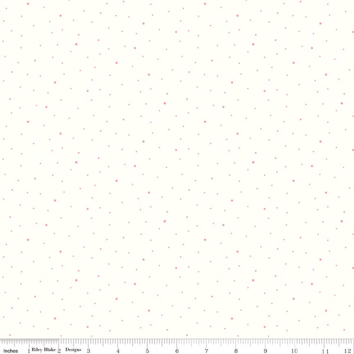 A close-up of a fabric pattern featuring small scattered pink dots on a warm off-white background, with a ruler along the bottom edge showing scale.