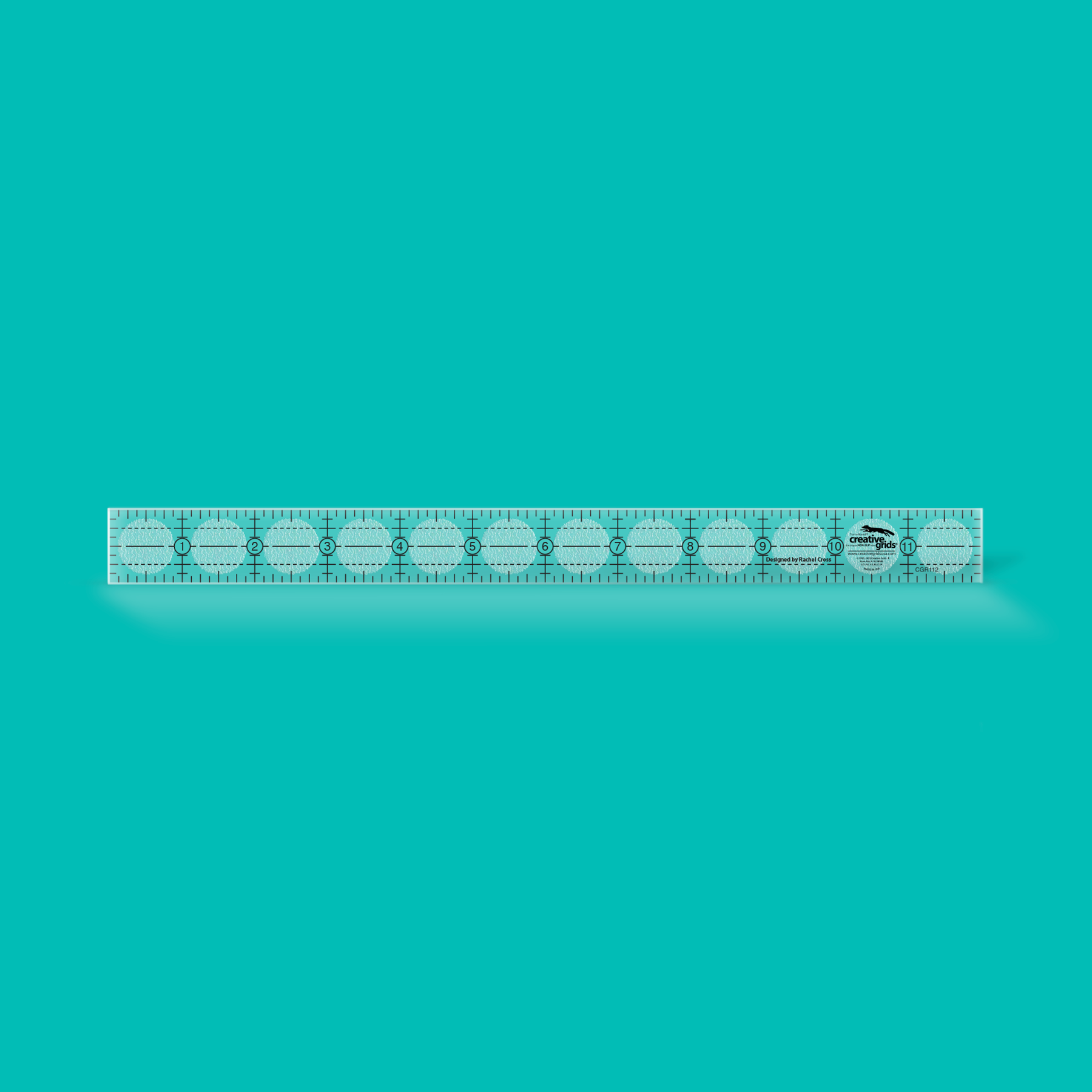 A clear plastic ruler with black measurement markings and a small black-and-white logo near the right end, shown horizontally on a solid turquoise background.