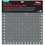 A 14x14 inch creative grids self-healing rotating cutting mat in dark gray with light blue grid lines and white measurement markings, shown on its black retail backing card.