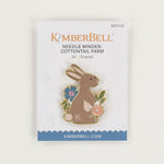 A KimberBell enamel pin of a brown bunny with flowers, mounted on its original white backing card with blue and orange branding.