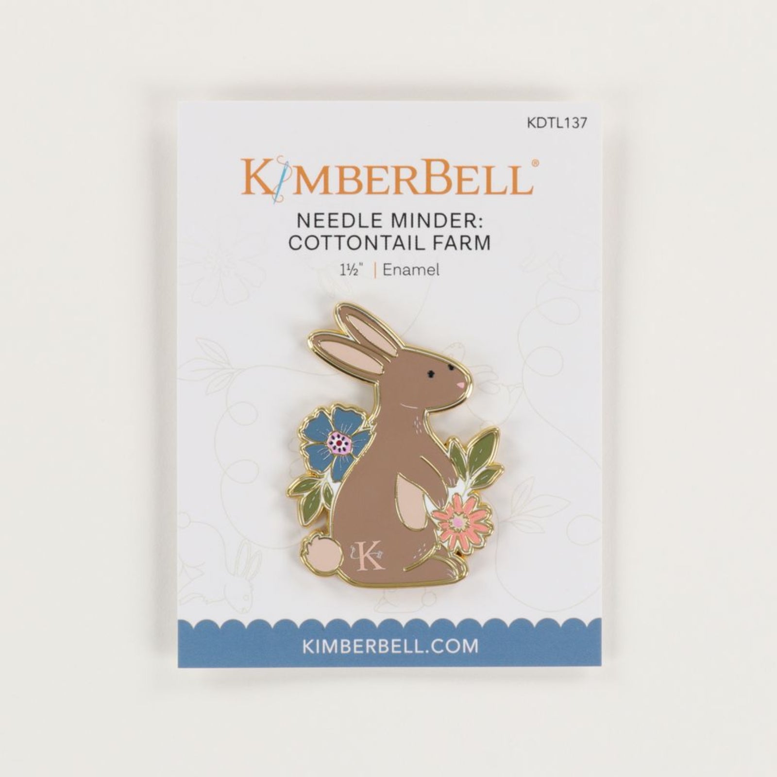 A KimberBell enamel pin of a brown bunny with flowers, mounted on its original white backing card with blue and orange branding.