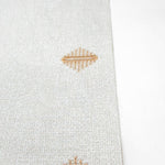 Light fabric with embroidered decorative buttonhole motifs stitched in golden thread.