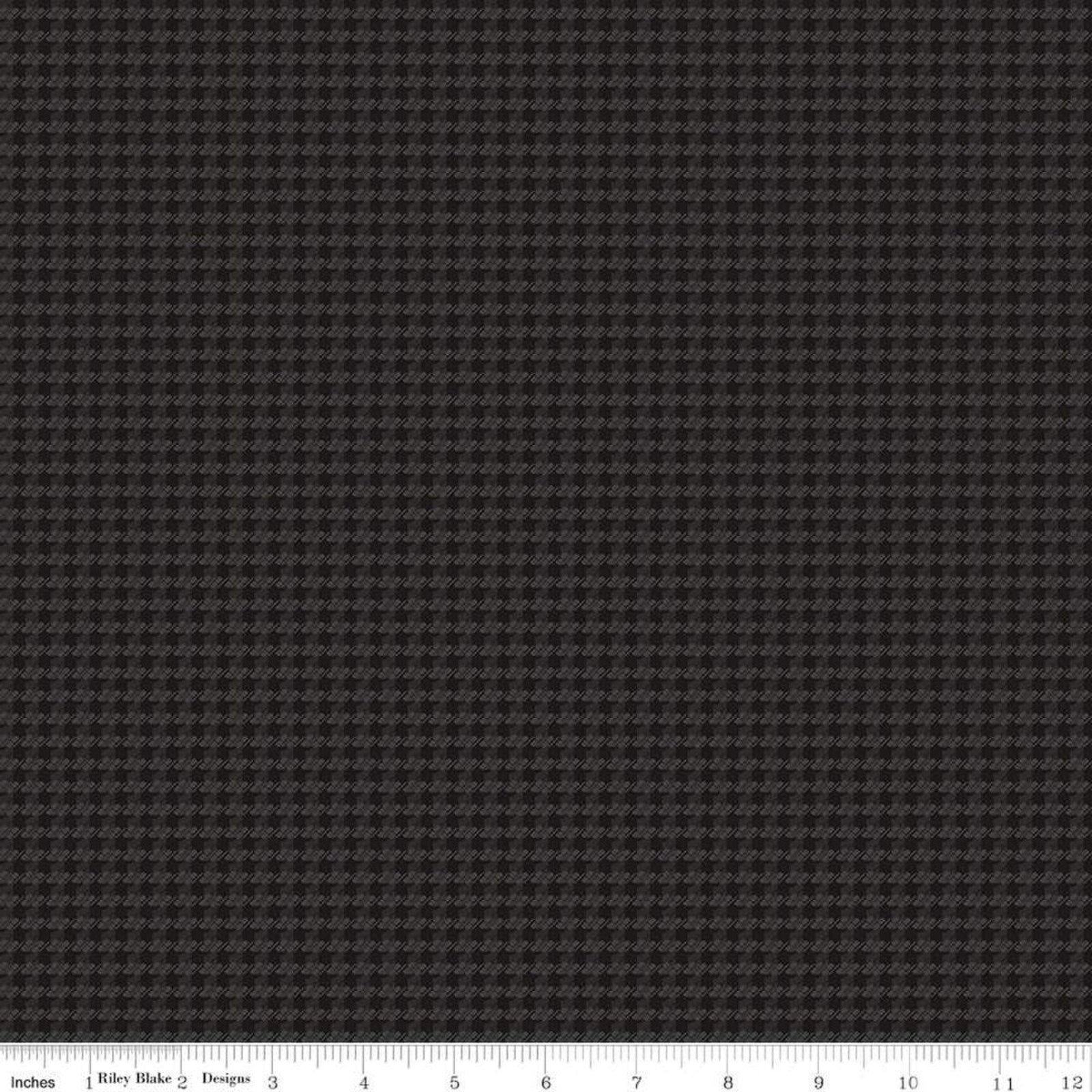 A close-up fabric swatch showing a dark charcoal gray and black micro-houndstooth pattern, with a ruler at the bottom indicating scale.