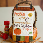 A decorative autumn-themed sign hanging from a basket handle, featuring the phrase 'Pumpkin Spice & everything nice.