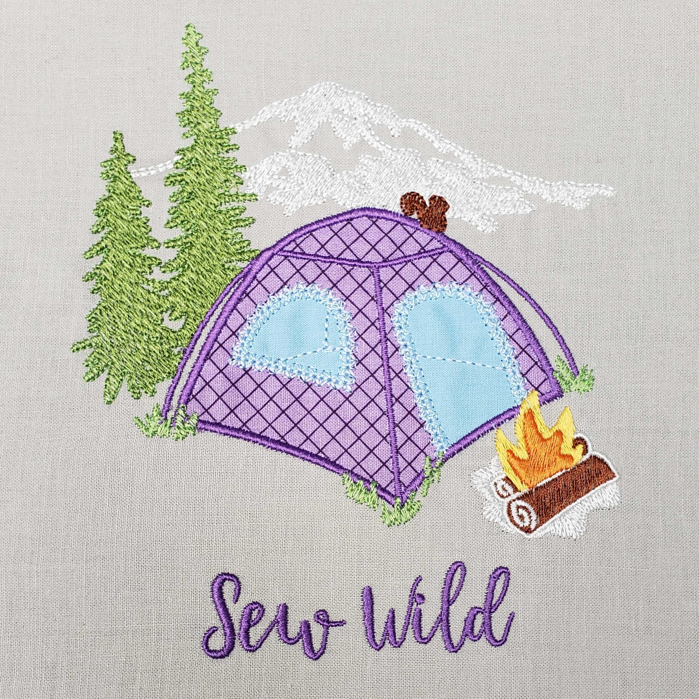 Embroidered design of a purple tent with trees and a campfire on gray fabric, featuring the text 'Sew Wild'.