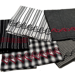 Group of black‑and‑white patterned napkins featuring decorative embroidered borders in red and black thread.