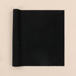 Rolled-up black velvet fabric on a beige background