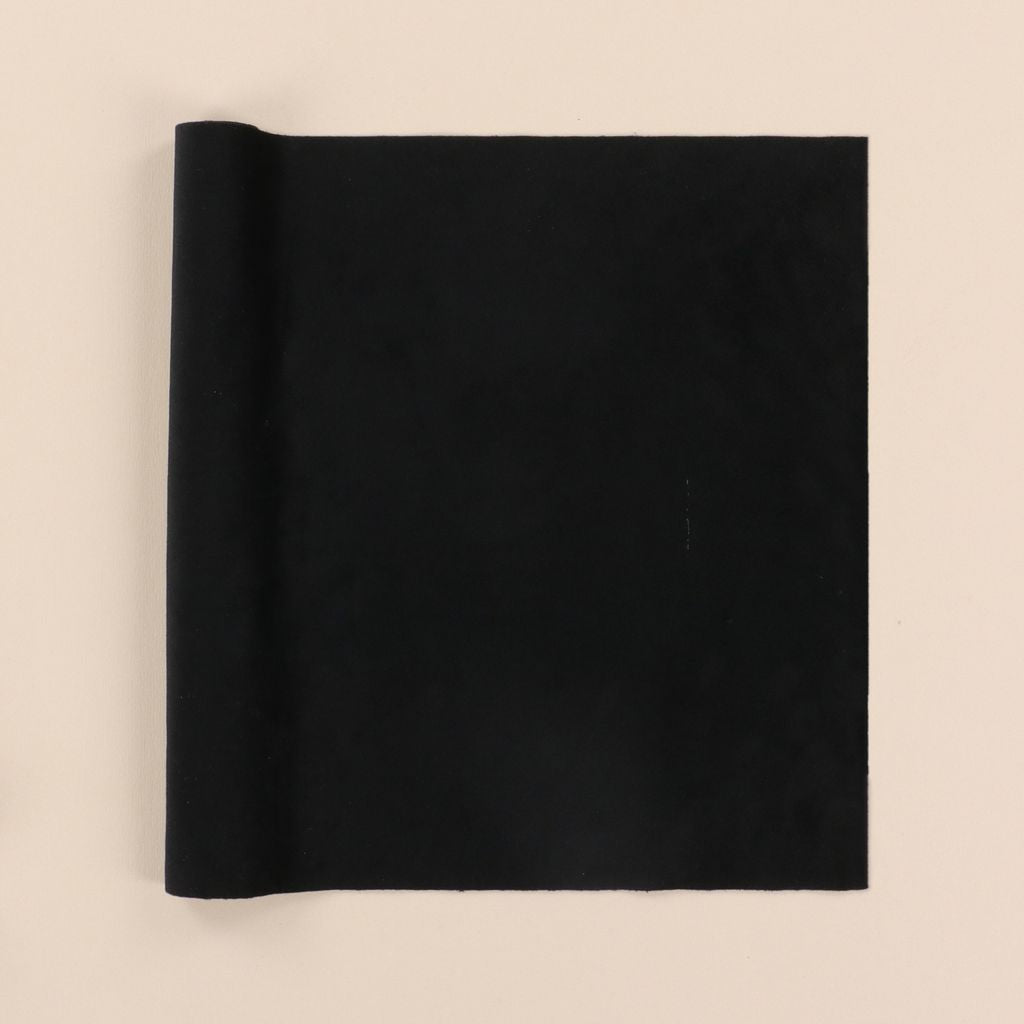 Rolled-up black velvet fabric on a beige background