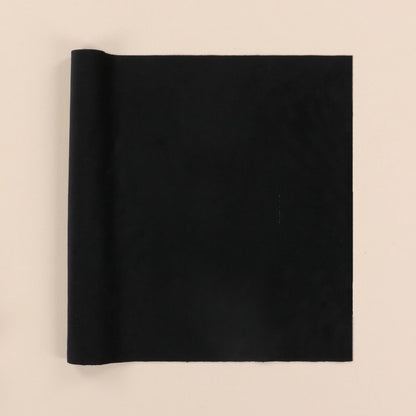 Rolled-up black velvet fabric on a beige background