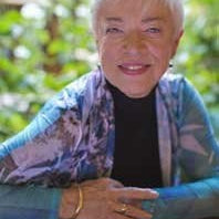 Outdoor portrait of instructor Nancy Chong seated in front of blurred green foliage.