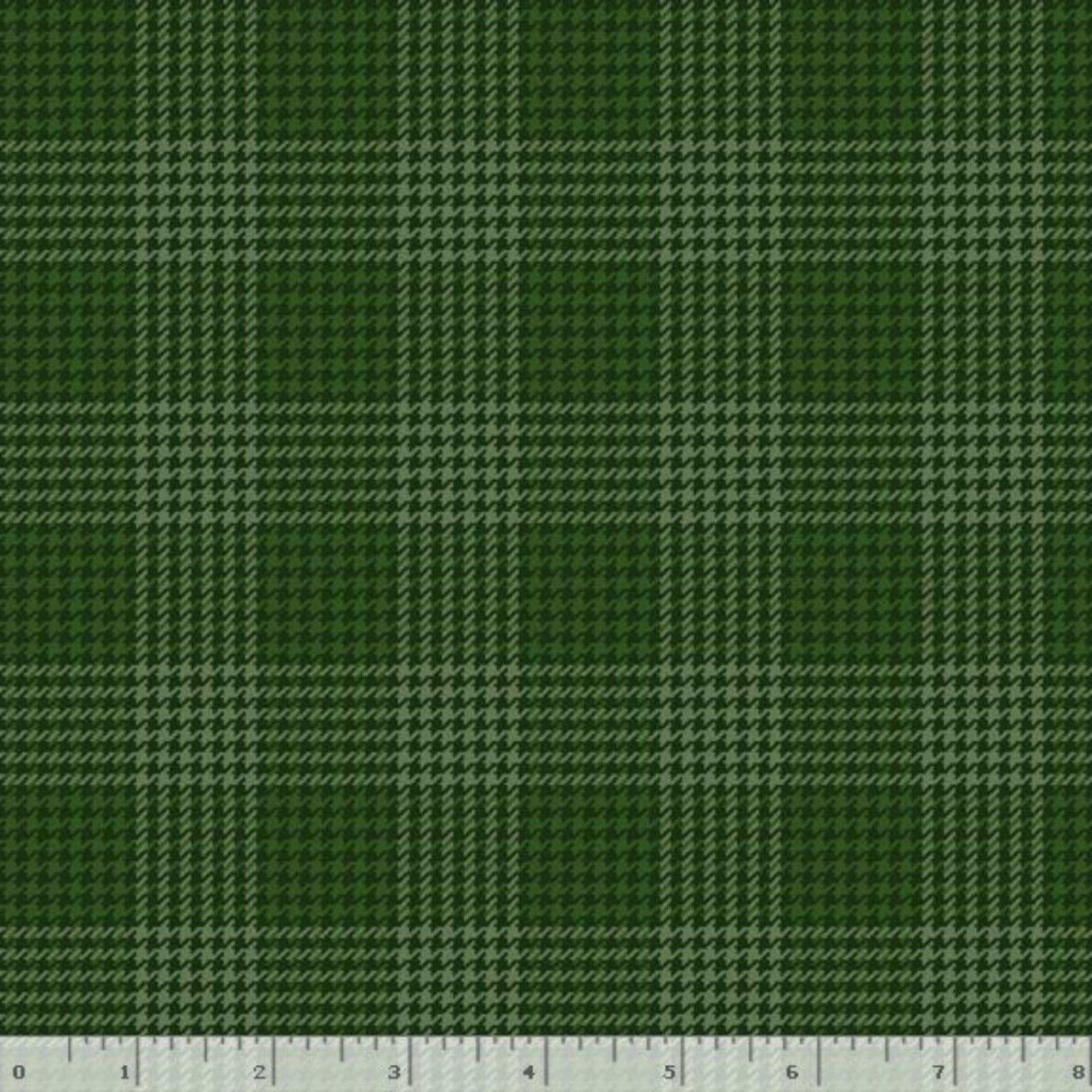 A close-up of a green plaid fabric pattern with a white ruler along the bottom edge showing scale.