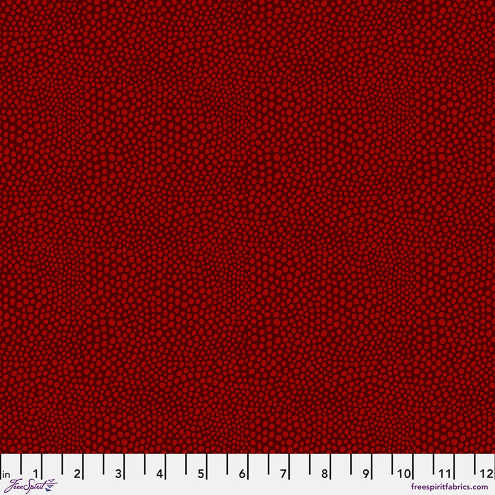 A close-up fabric pattern swatch showing a dense field of small dark red dots on a slightly darker red background, with a white ruler strip along the bottom edge for scale.