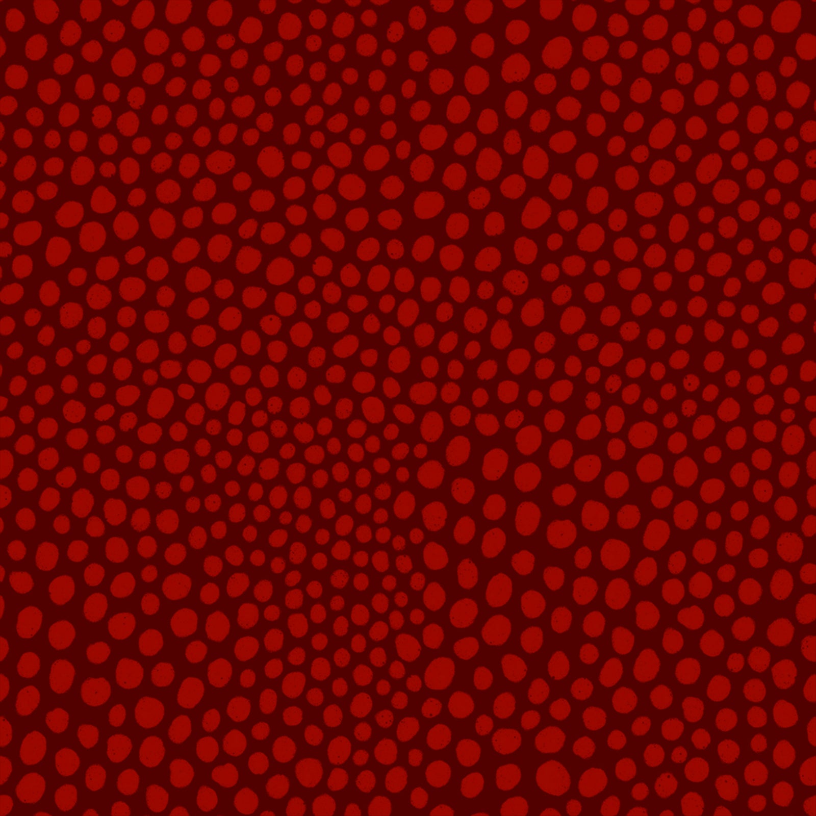 A close-up of a red patterned fabric or material featuring a dense field of small, slightly darker red oval dots arranged in a swirling, radial design.