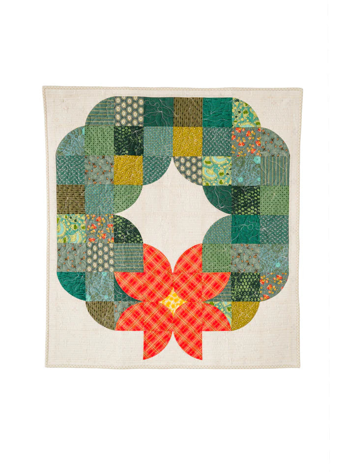 Posh Wreath quilt in bright green fabrics with layered curved blocks displayed on a dark wall.