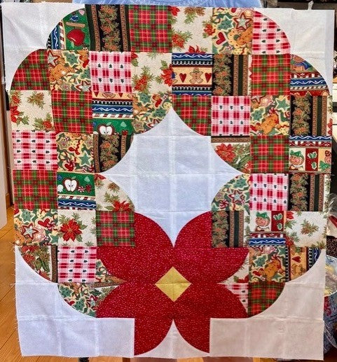 Posh Wreath quilt block made with festive holiday prints and a red poinsettia center before quilting.