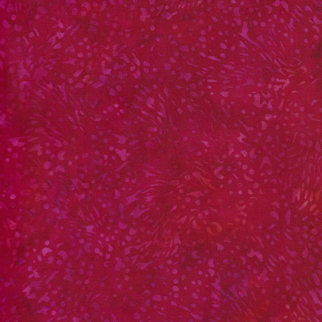 A close-up of a magenta and deep red patterned fabric with a batik-like textured design.