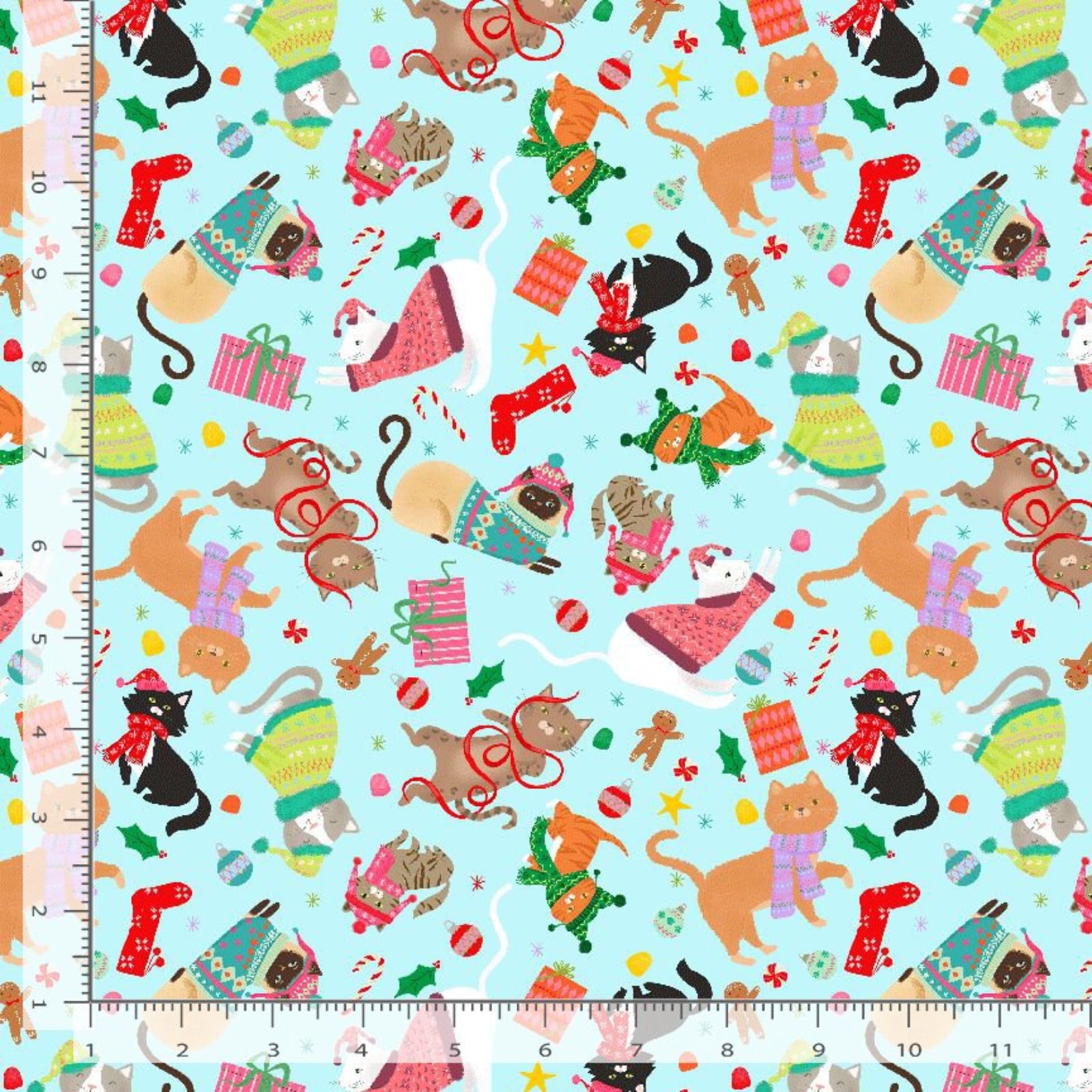 A close-up of a repeating holiday pattern on fabric, featuring illustrated cats in winter clothing, gifts, candy canes, stockings, and Christmas ornaments on a light aqua background. Measurement rulers are visible along the left and bottom edges.
