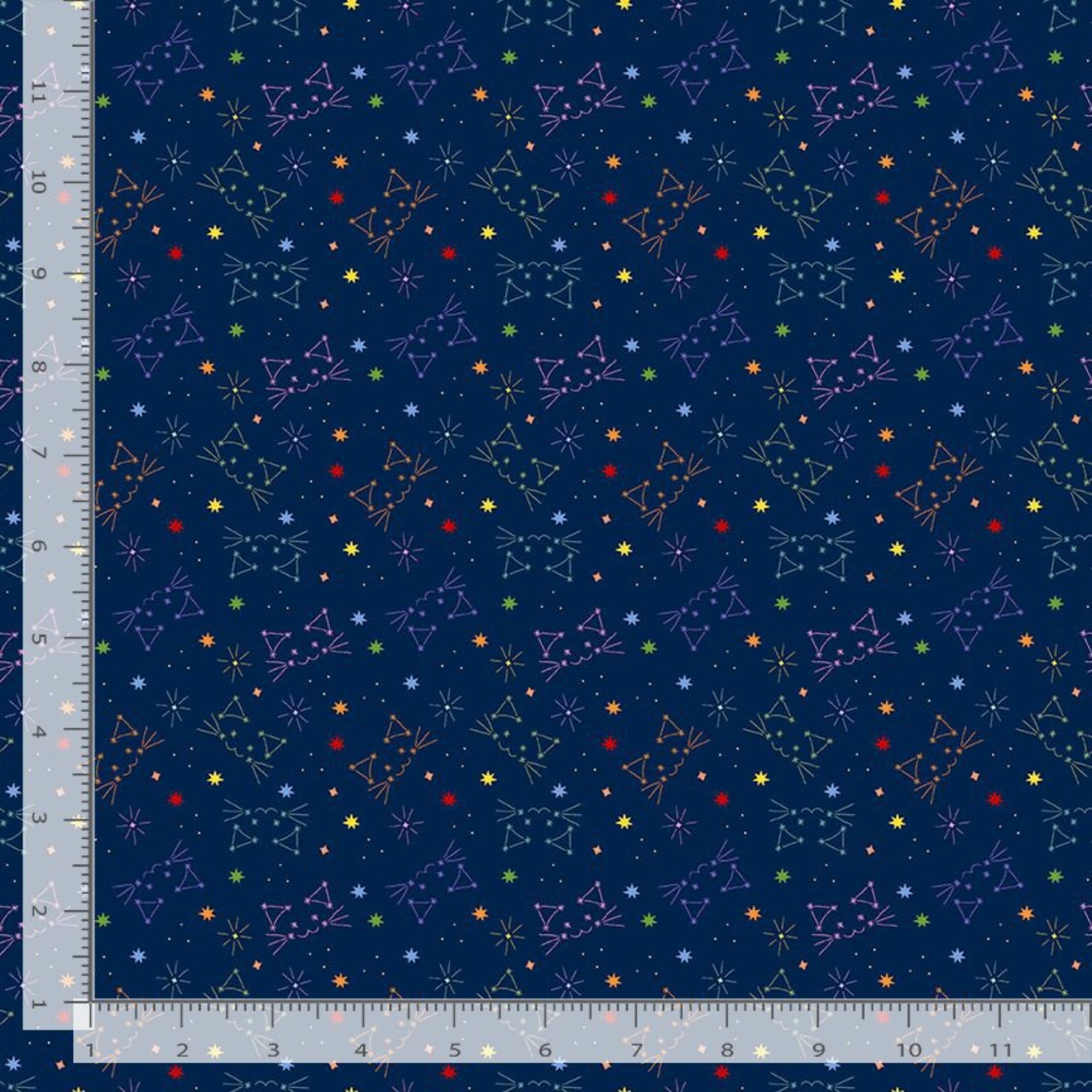 A close-up of a navy blue fabric with a repeating pattern of colorful constellations and small stars, shown with a ruler along the left and bottom edges for scale.